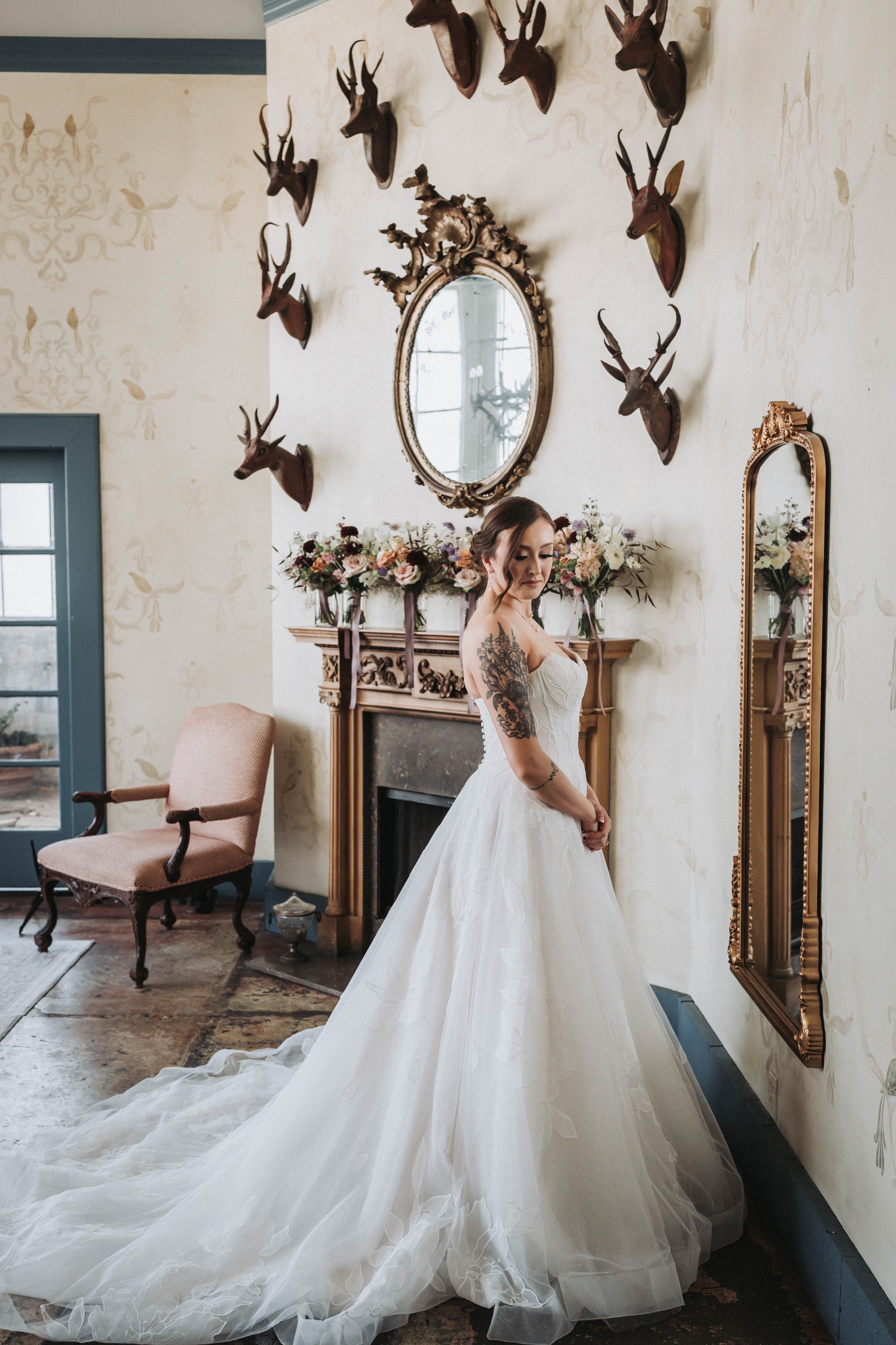 Bride in her gown beside a gilt mirror and marble fireplace as she finishes getting ready — Seattle, Washington wedding photography